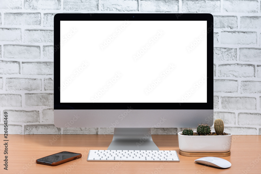 Blank screen of All in one Computer with smart phone and cactus pot on wooden table, White brick wall background Blank screen of All in one Computer with smart phone and cactus pot on wooden table, White brick wall background