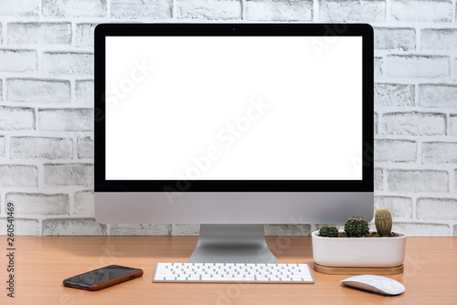 Blank screen of All in one Computer with smart phone and cactus pot on wooden table, White brick wall background