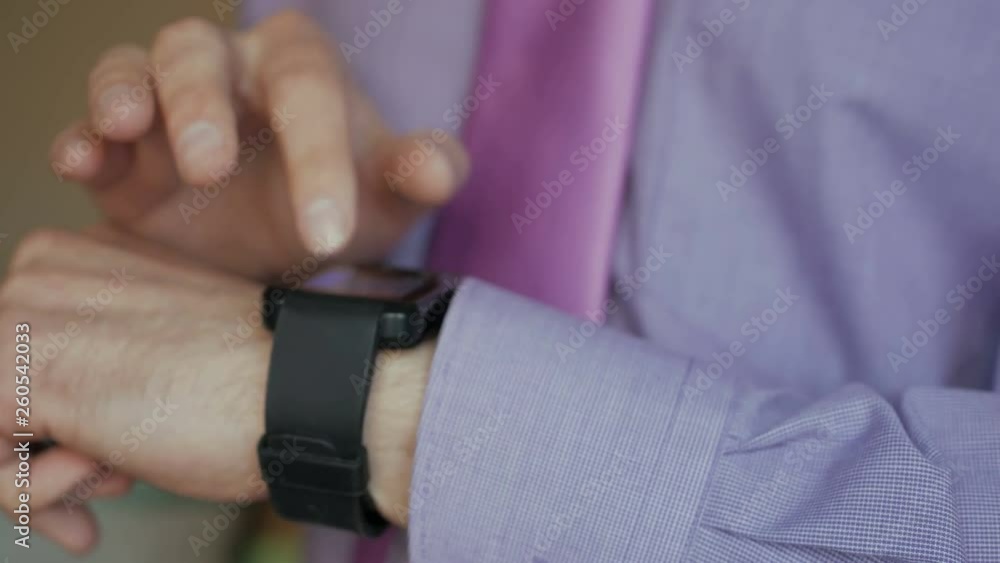 Man using his smartwatch app. Closeup. Businessman using trendy smart watches mobile application on touch screen. Guy using her smartwatch touch screen wearable technology device. Close Up. Man using his smartwatch app. Closeup. Businessman using trendy smart watches mobile application on touch screen. Guy using her smartwatch touch screen wearable technology device. Close Up.