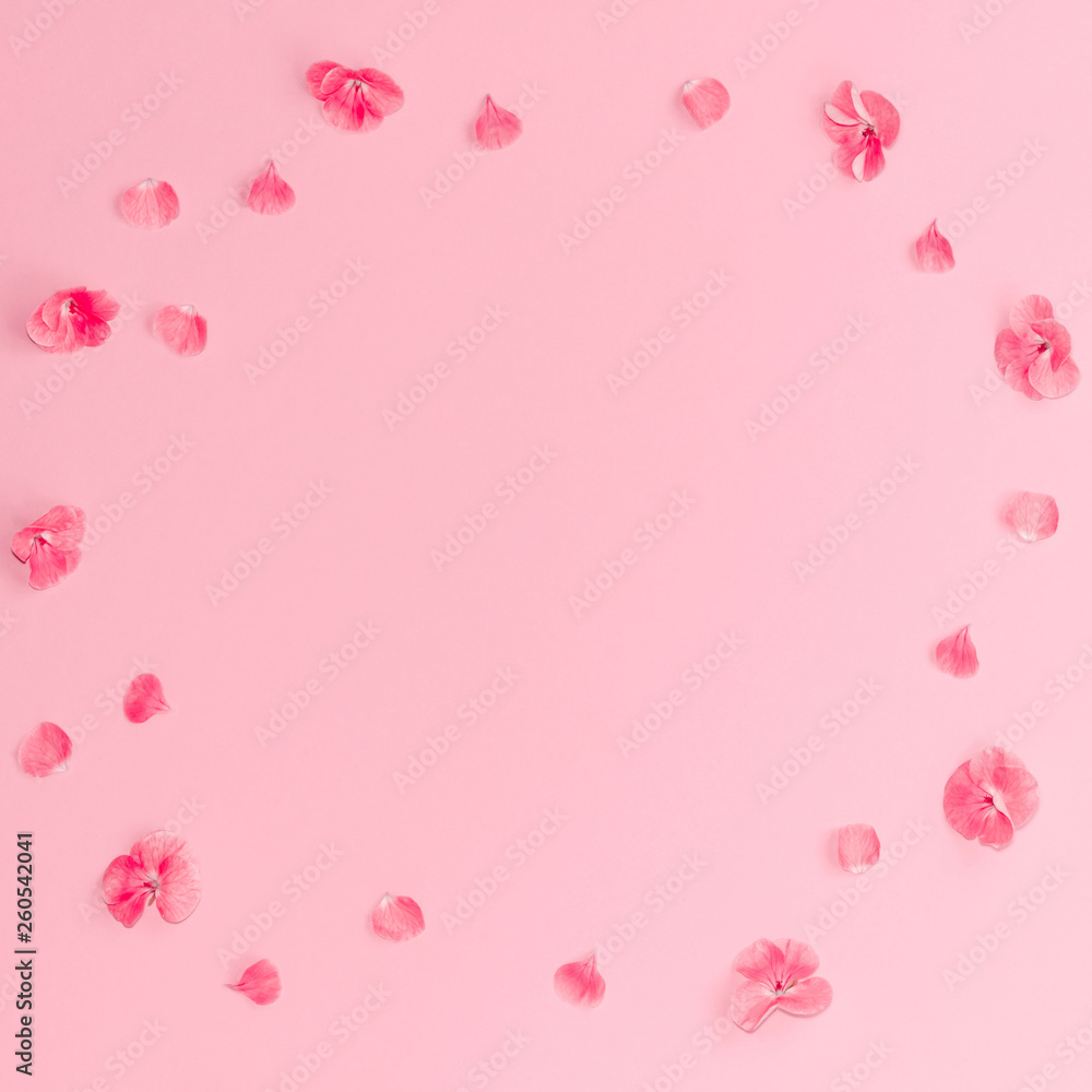 Flat lay composition of pink flowers in a circle on pastel pink background.