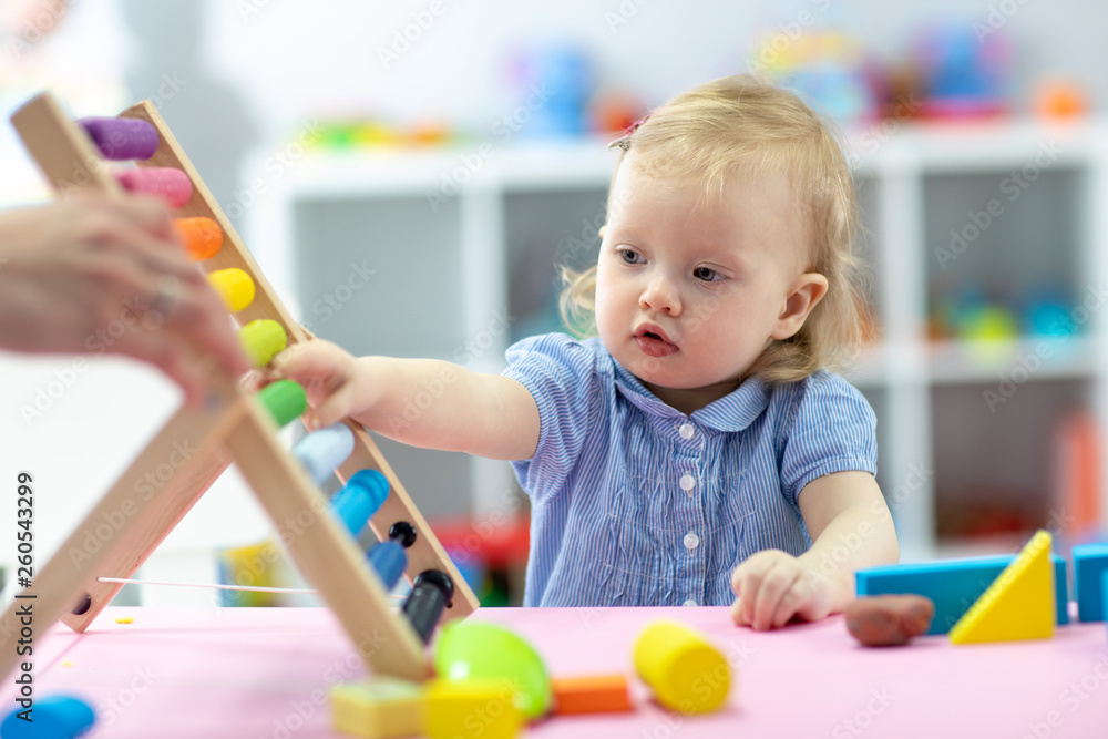 Little kid girl plays with abacus sitting at table Little kid girl plays with abacus sitting at table