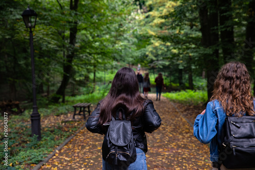 two young girls with backpacks walking by city park.