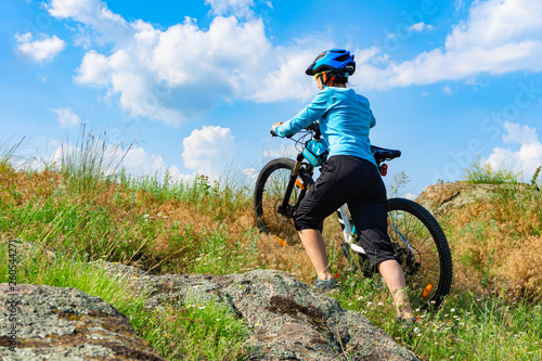 Woman cyclist pushing her bike up a steep slope.