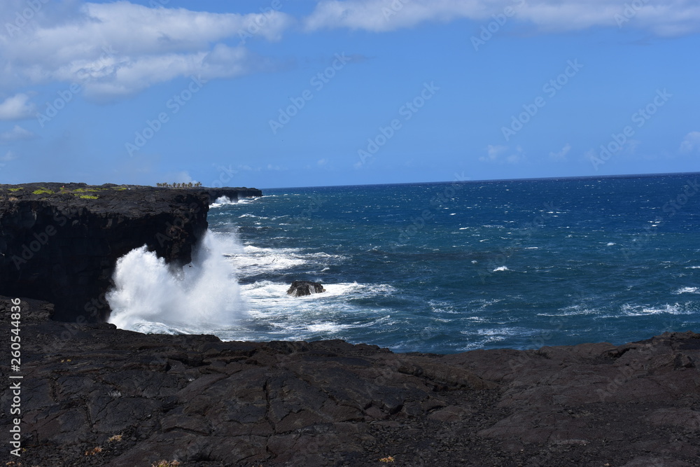 Sea Cliff at Volcano National Park HI waves crashing against volcanic rock creating foam and surf