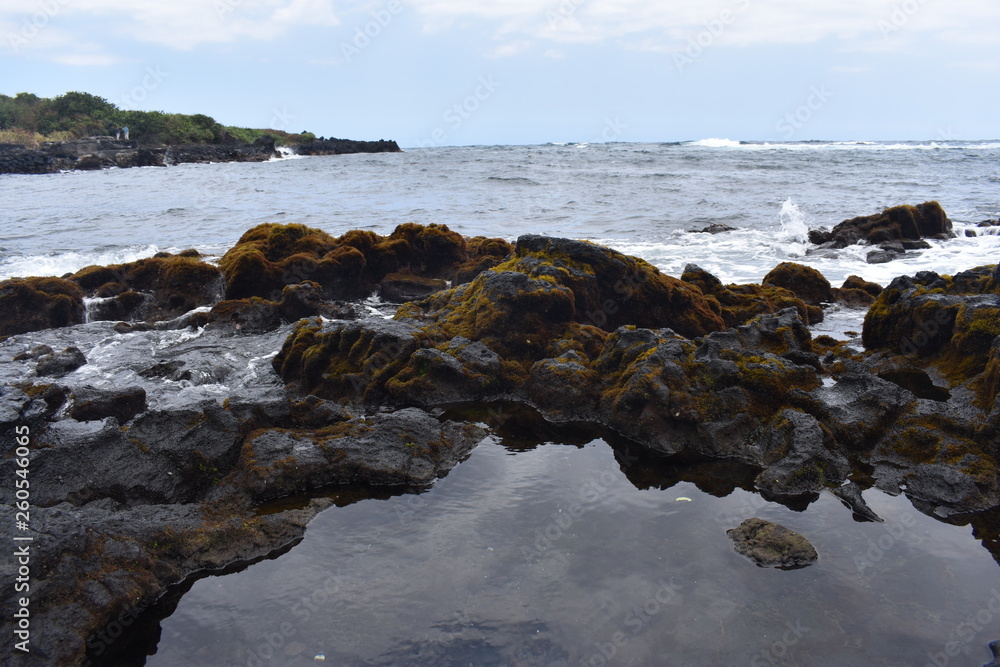 Waves Crashing on Rocky Shore in Hawaii white foam as the waves wash over the rocks under a blue sky Waves Crashing on Rocky Shore in Hawaii white foam as the waves wash over the rocks under a blue sky