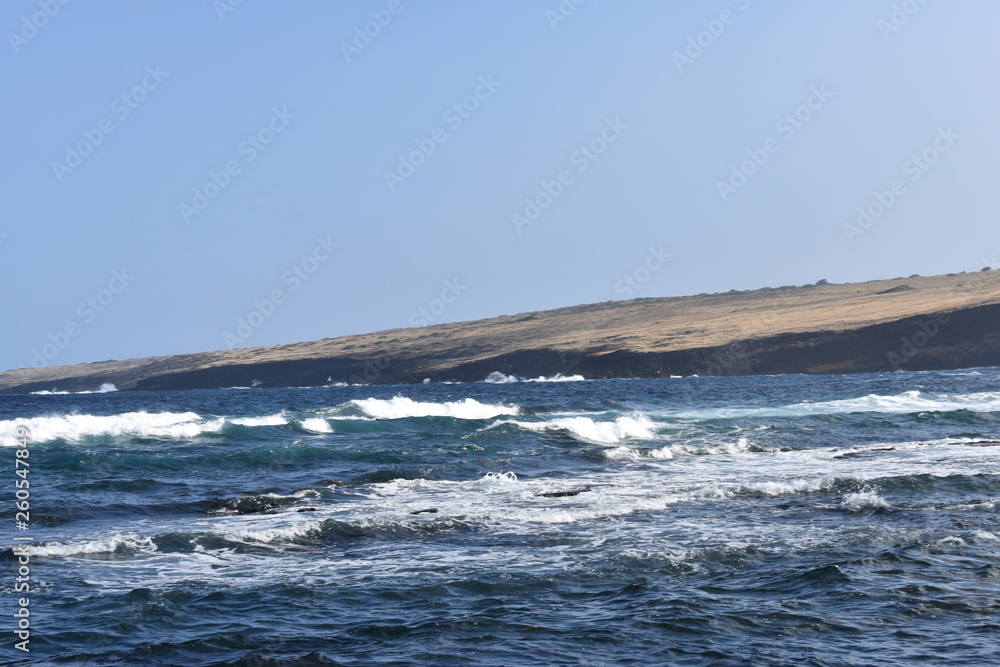 Waves Crashing on Rocky Shore in Hawaii white foam as the waves wash over the rocks under a blue sky Waves Crashing on Rocky Shore in Hawaii white foam as the waves wash over the rocks under a blue sky