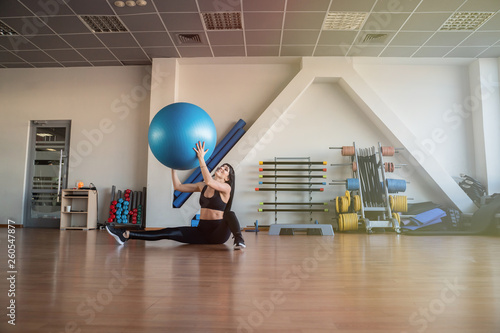 Young and athletic girl using fitness ball in a gym. Fitness ball at gym workout fitness and pilates exercise.Young woman doing some pilates exercises with a ball