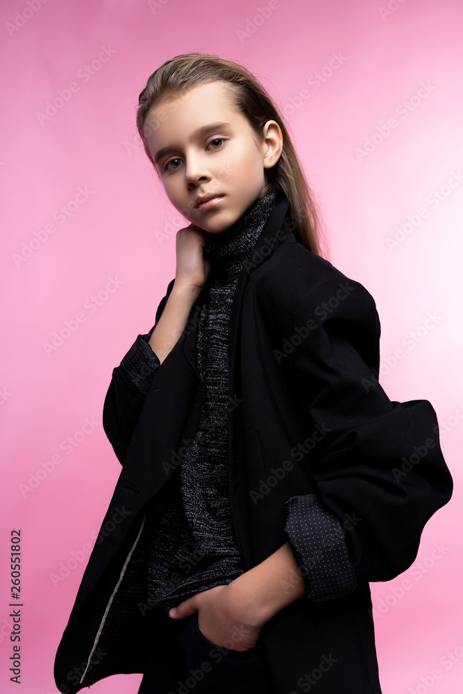 Naklejka premium Fashionable portrait of beautiful cute teen girl wearing a gray turtleneck, jeans and blazer jacket. Pink background. Advertising, trendy and commercial design