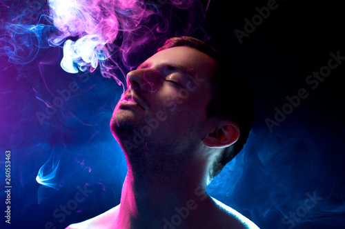 man on a blue background exhales smoke photo