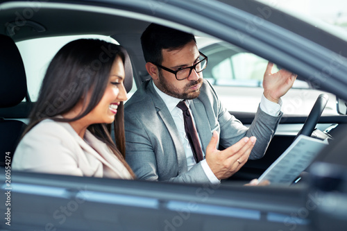 Attractive saleswoman showing inside of a car to customer