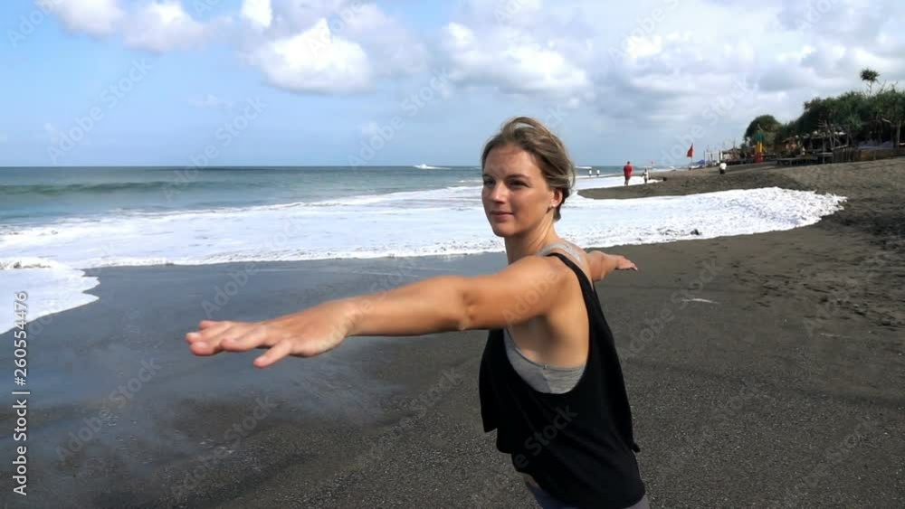 Young, fit woman stretching arms, exercising on the beach, slow motion Young, fit woman stretching arms, exercising on the beach, slow motion
