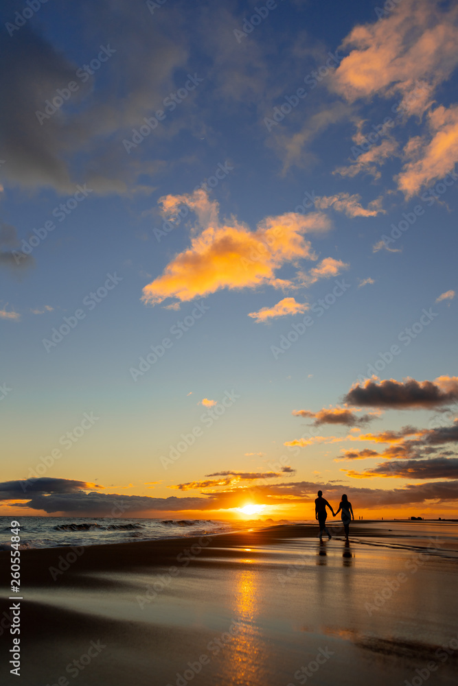 happy couple walking on seashore on a beach vacation or honeymoon trip