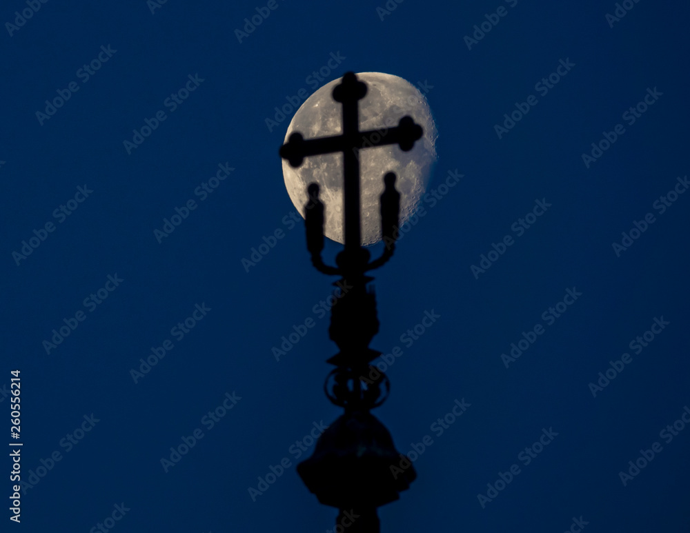 Silhouette on the top of a church with the moon in the background