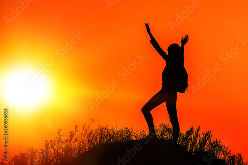 silhouette of a girl with her hands up on top of the mountain against the evening sky. success  achievement of goals.