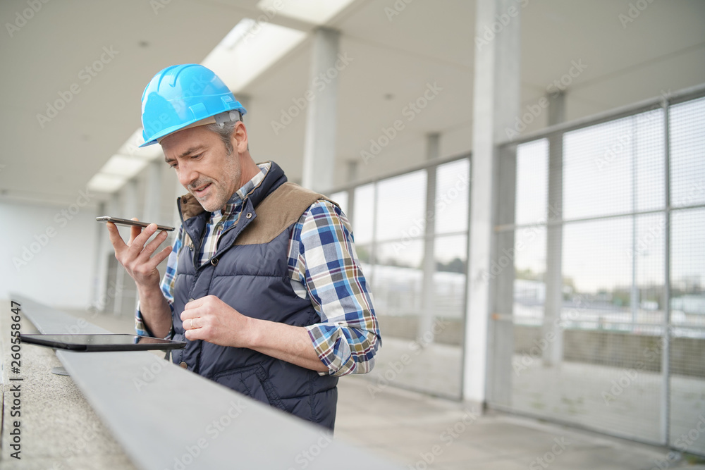 Architect on cellphone checking worksight progress Architect on cellphone checking worksight progress