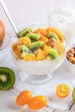 Close-up glass bowl with yogurt and fruits on white napkin.