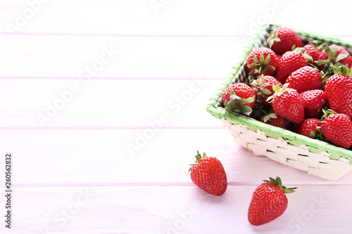 Fresh strawberries in basket on pink wooden table
