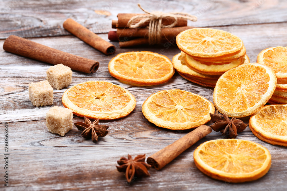 Dried orange fruits with cinnamon, star anise and sugar cubes on brown wooden table