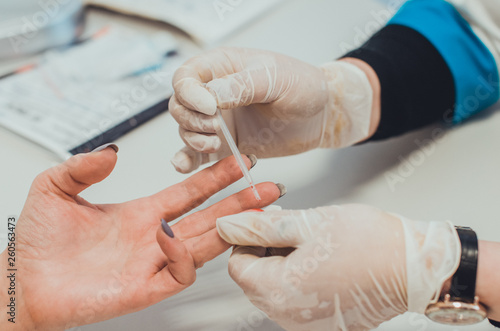 A doctor in medical laboratory taking a blood test with a pipette. Hands closeup. Concept of a checkup for viruses  cancer and HIV infection test