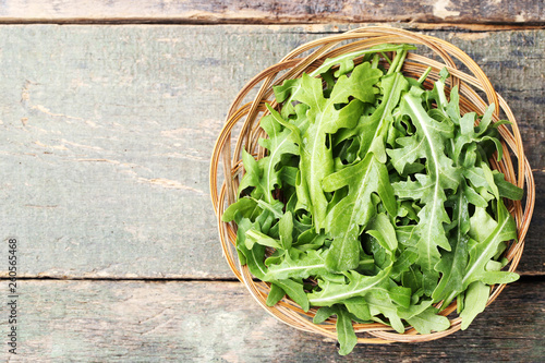 Green arugula leafs in basket on wooden table