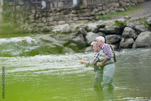 Fly fishing expert guiding novice in river