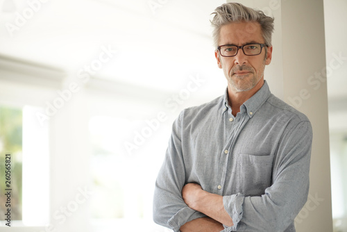Portrait of handsome mature man wearing glasses smiling at camera