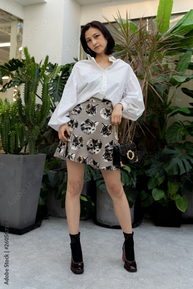 Asian chinese girl modeling with mini skirt and white shirt. elegant look,  holding a tote bag in black boots, Stock Photo | Adobe Stock