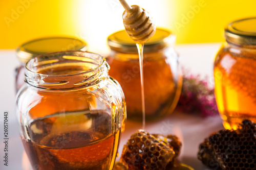 Honey in jar with honey dipper on wooden background