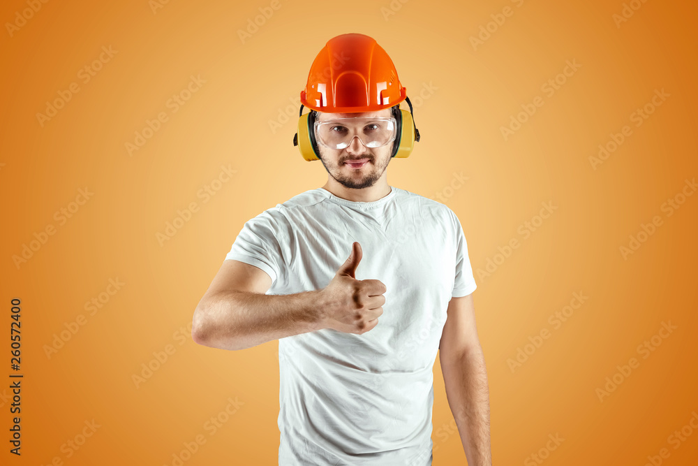 Male builder in orange helmet on an orange background. Concept of construction, contractor, repair.