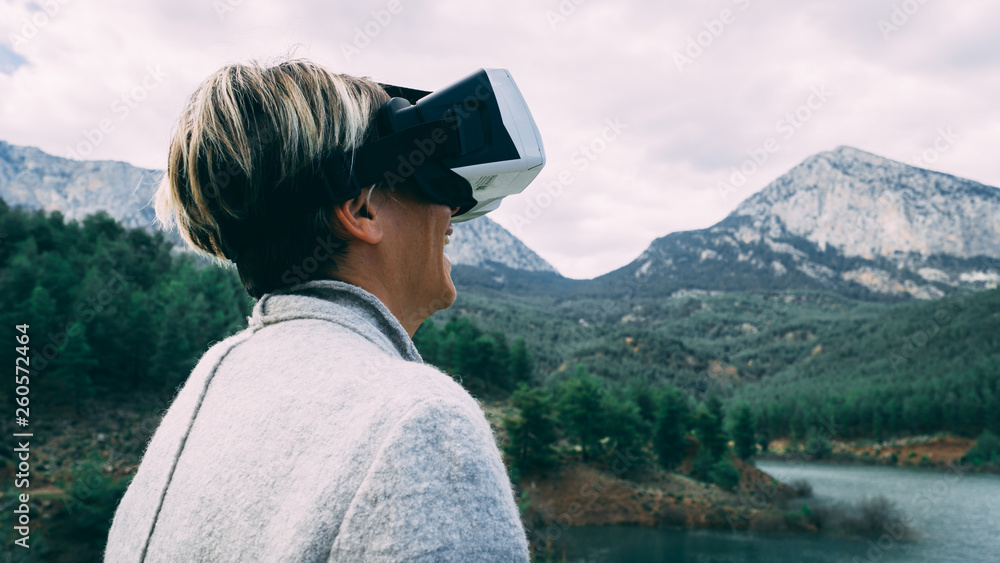 Woman in the nature wearing augmented reality goggles. Adult female having fun with AR glasses on. Flying. Playing. Daytime.
