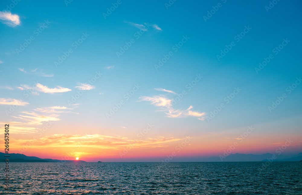 Naklejka premium beautiful sunset over the sea on a background of mountains