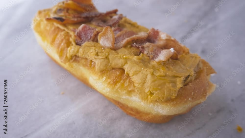 Gourmet maple bacon glazed donut falling in slow motion. The popular food trend combines sweet and savory in a breakfast pastry to celebrate National Donut Day. Gourmet maple bacon glazed donut falling in slow motion. The popular food trend combines sweet and savory in a breakfast pastry to celebrate National Donut Day.