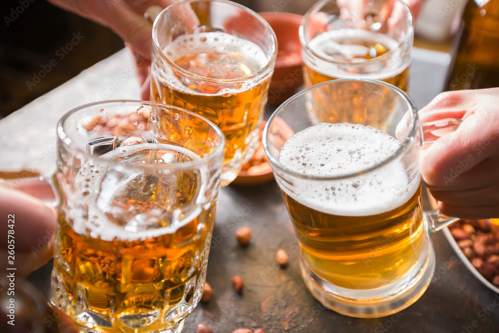 A group of friends are drinking beer from mugs in a bar at the table. A group of friends are drinking beer from mugs in a bar at the table.