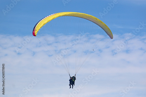 Tandem paraglider flying yellow wing