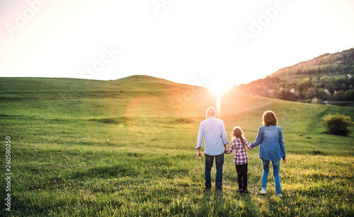 Senior couple with granddaughter outside in spring nature  walking at sunset.