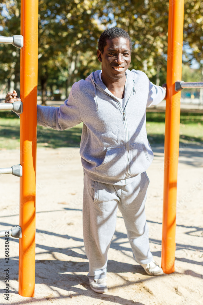 Fototapeta premium Athletic african american male performs warm-up exercises at chin-up bar