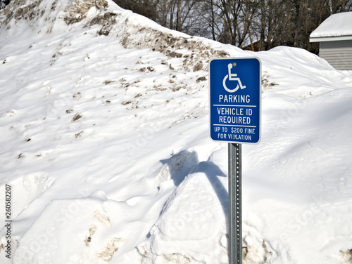 Obraz na płótnie Handicapped parking sign in front of large pile snow parking lot in winter. w salonie