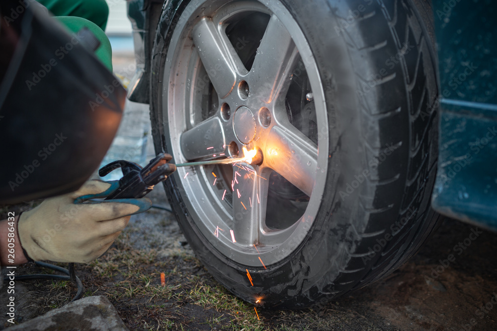Man work with welding. Mechanical tools for auto service and car repair in Car repair shop and Worker repairing car.Car wheel repair Man work with welding. Mechanical tools for auto service and car repair in Car repair shop and Worker repairing car.Car wheel repair