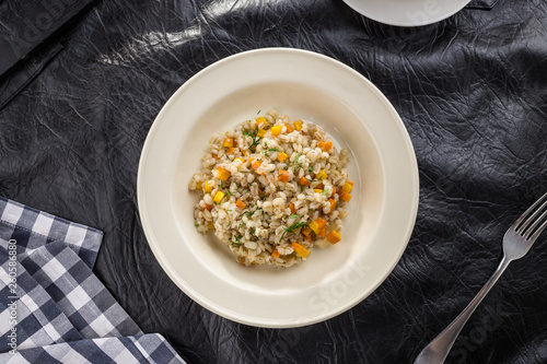Tasty Pearl barley porridge with carrot on black table