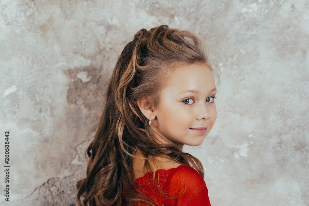 portrait of a smiling young girl in a red dress and with a beautiful hairstyle. studio shot portrait of a smiling young girl in a red dress and with a beautiful hairstyle. studio shot