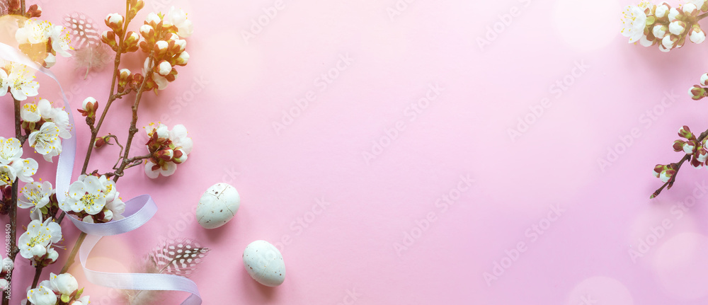 Easter greeting card with easter eggs and sprin flowers on pink table. Top view with space for your greetings - Image