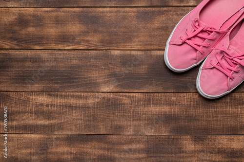 Pink sneakers on wooden background.