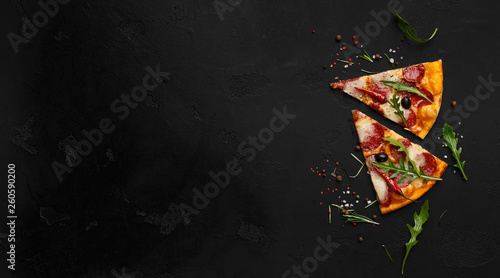 Two slices of pizza with rocket salad and spices, copy space