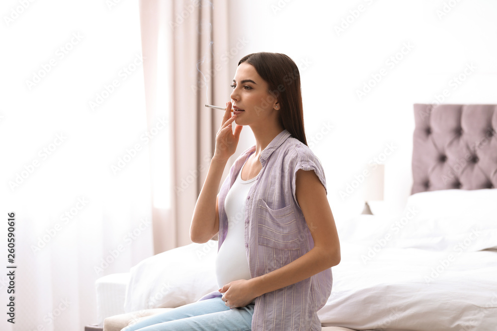 Young pregnant woman smoking cigarette at home Young pregnant woman smoking cigarette at home