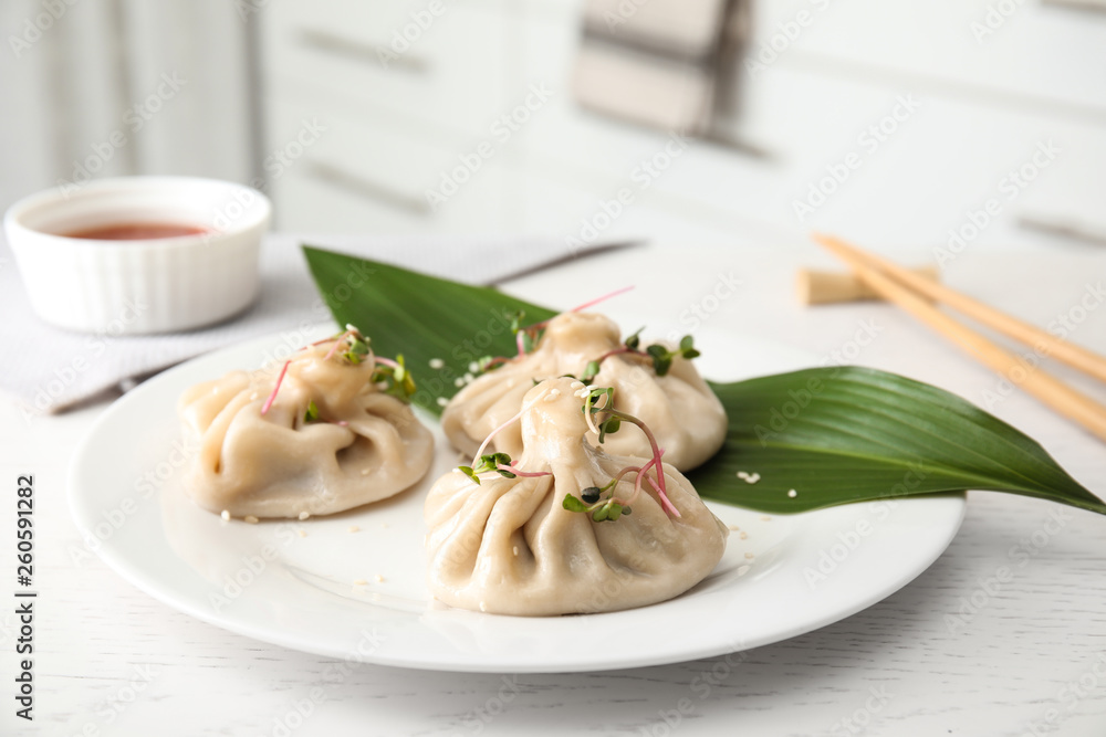 Plate with tasty baozi dumplings on white wooden table