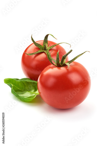 Fresh juicy tomatoes with green basil leaves, close-up, isolated on white background