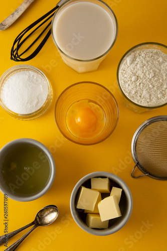 Ingredients for baking pastry or dessert - butter, flour, eggs, milk, sugar. Yellow background, flat lay. Dessert recipe, cooking process. Copy space.