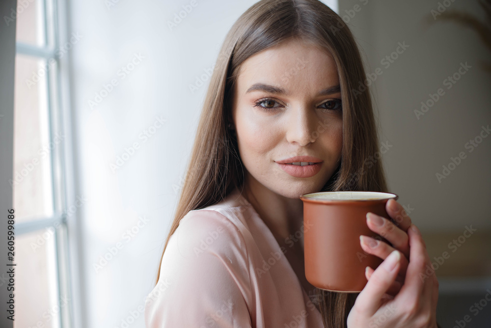 Beautiful girl is drinking coffee and smiling while sitting at the cafe Beautiful girl is drinking coffee and smiling while sitting at the cafe