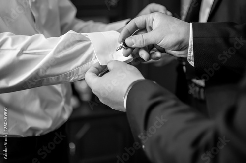 A groom fastening a cuff-link before getting married