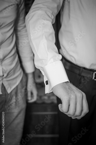 A groom fastening a cuff-link before getting married
